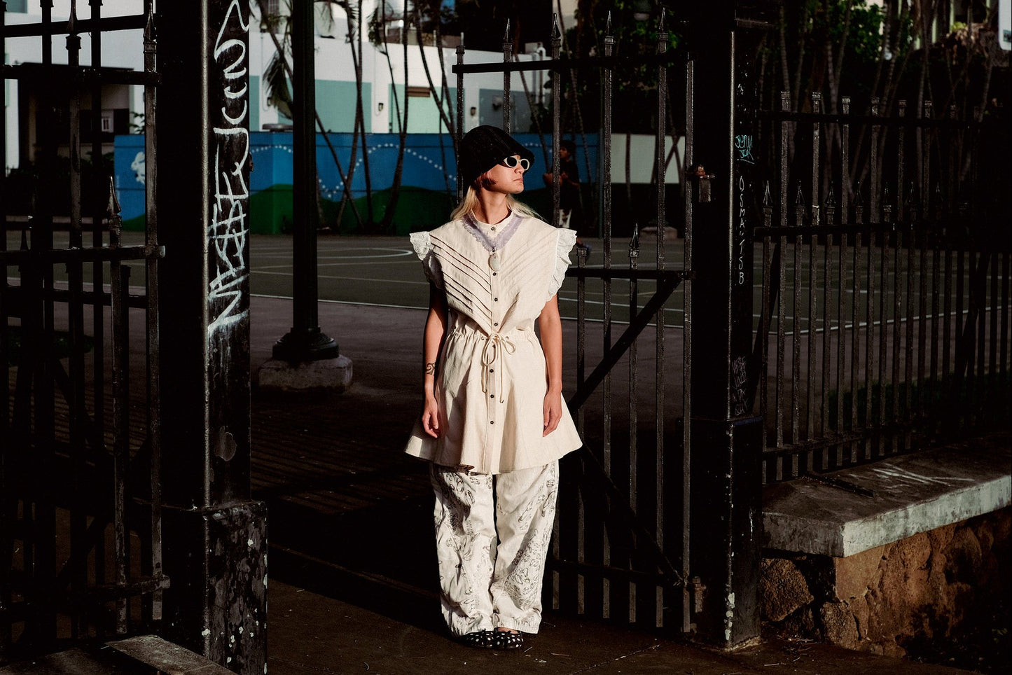 Person wearing a white dress standing in front of a gate with a blurred background