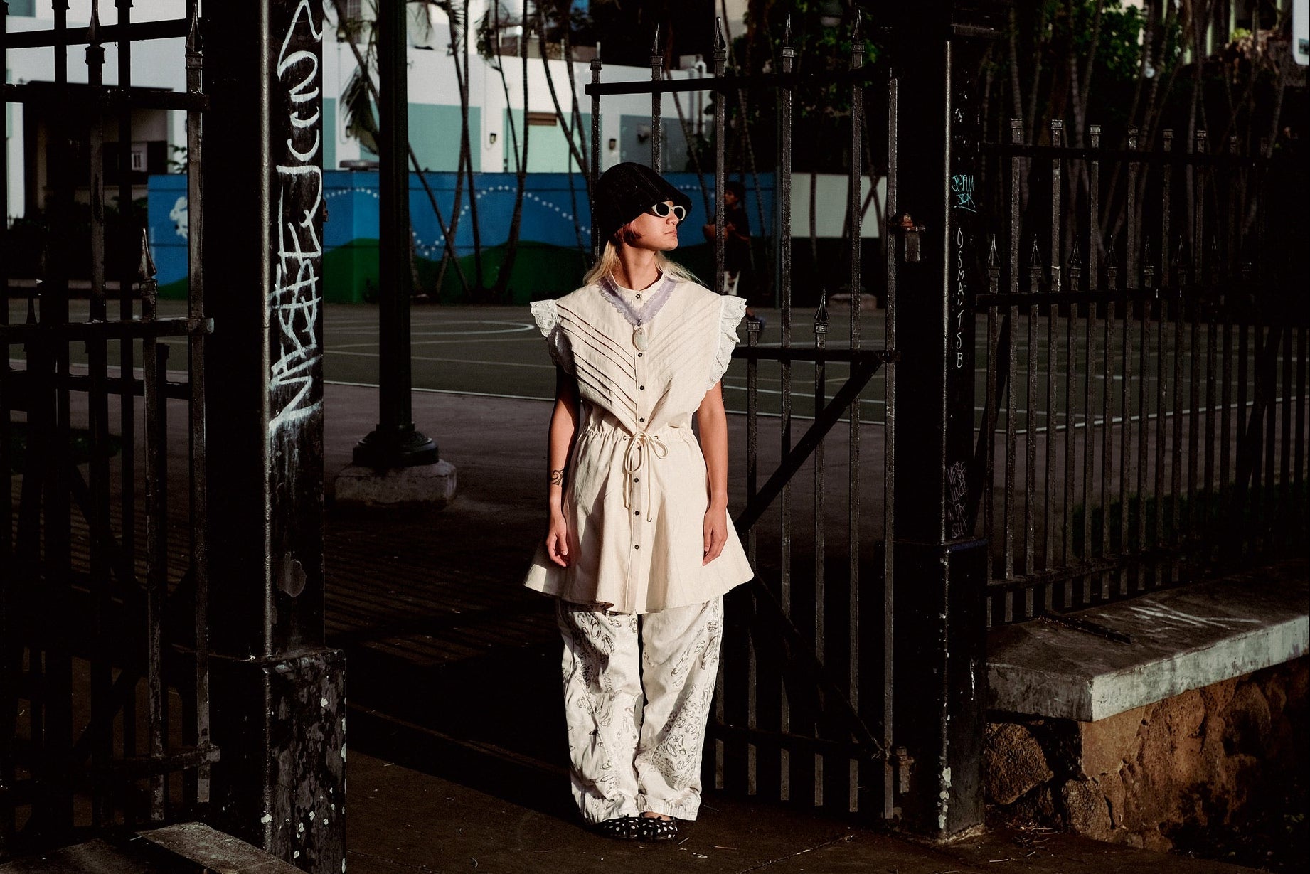 Person wearing a white dress standing in front of a gate with a blurred background